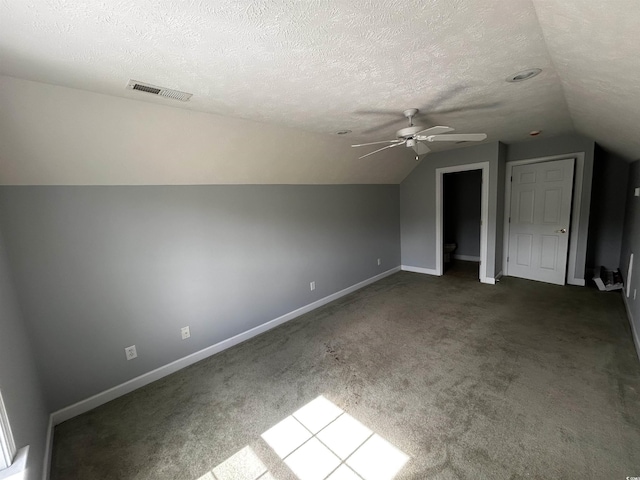 additional living space featuring a textured ceiling, lofted ceiling, visible vents, baseboards, and carpet