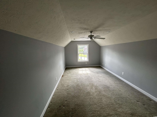 additional living space with carpet, vaulted ceiling, a textured ceiling, and baseboards