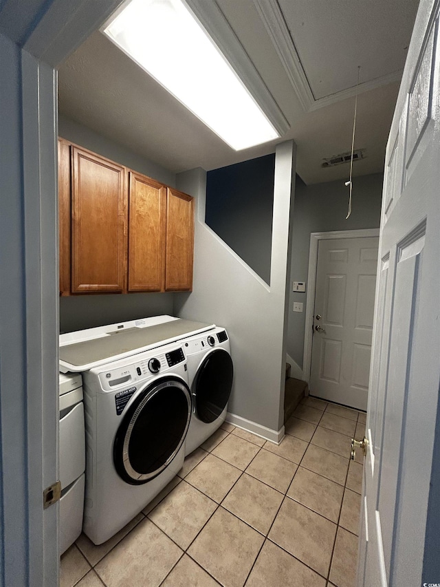 clothes washing area with light tile patterned floors, cabinet space, visible vents, attic access, and separate washer and dryer