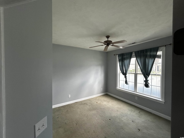 carpeted spare room with a textured ceiling, a ceiling fan, and baseboards