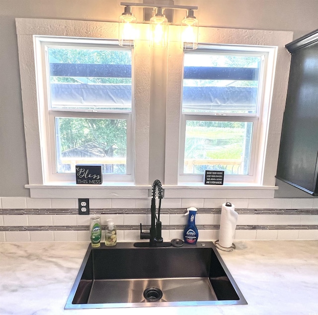 kitchen featuring sink, decorative backsplash, hanging light fixtures, and a healthy amount of sunlight