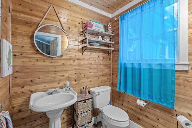 bathroom featuring toilet, sink, and wood walls