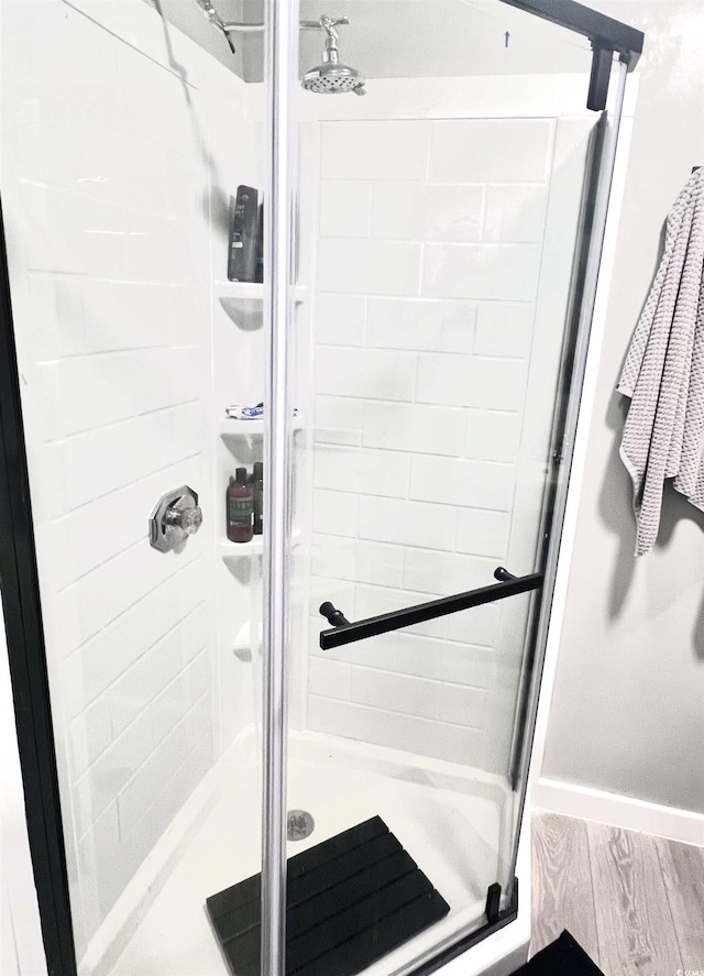 bathroom with hardwood / wood-style flooring and a shower with door