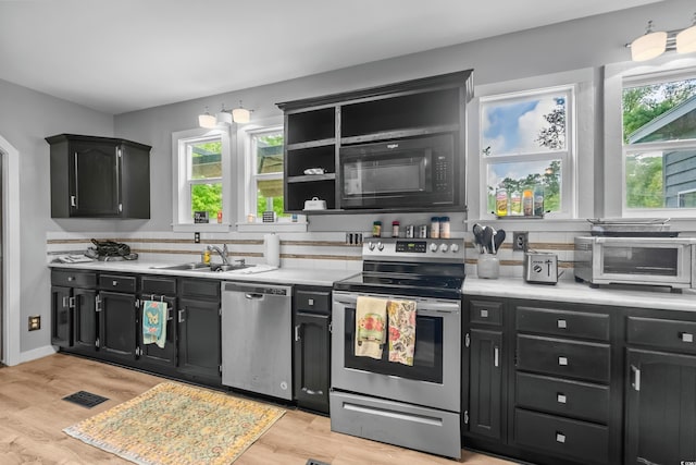 kitchen featuring appliances with stainless steel finishes, light hardwood / wood-style floors, sink, and a wealth of natural light