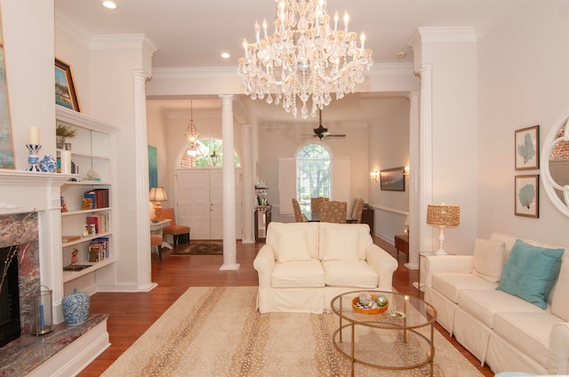 living room featuring ornate columns, ceiling fan with notable chandelier, wood-type flooring, and a premium fireplace