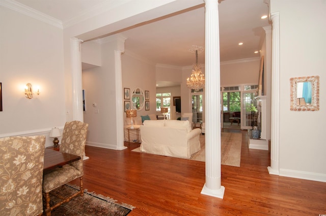 interior space with hardwood / wood-style flooring, decorative columns, and ornamental molding