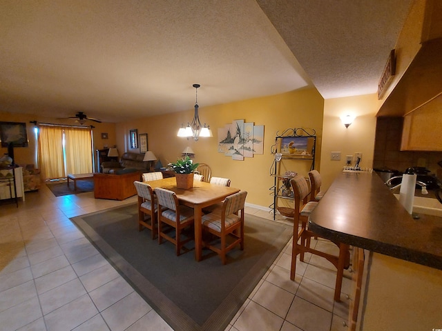 dining space with a textured ceiling, light tile floors, and ceiling fan with notable chandelier