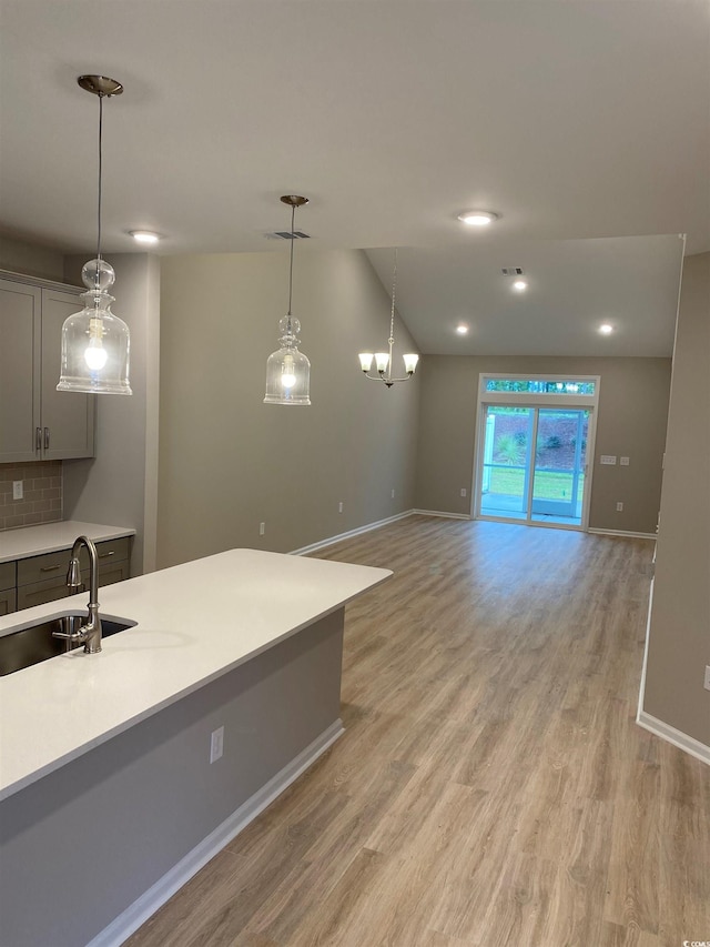 kitchen featuring gray cabinets, light hardwood / wood-style flooring, sink, and decorative light fixtures