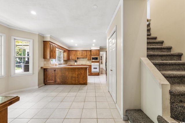 kitchen with decorative backsplash, kitchen peninsula, ornamental molding, and white oven