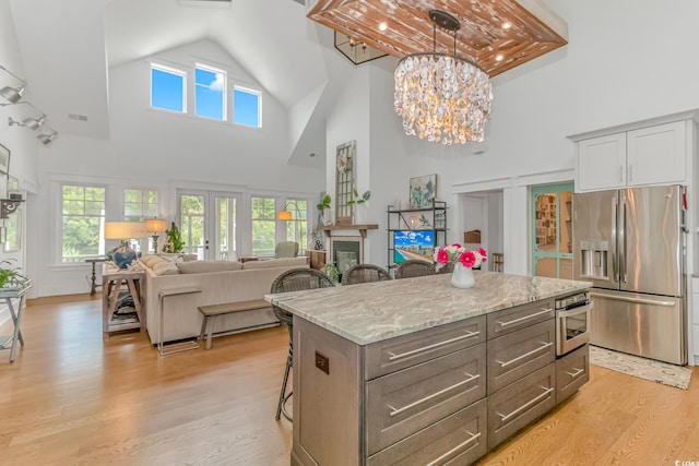 kitchen featuring pendant lighting, stainless steel appliances, a center island, a kitchen bar, and light wood-type flooring