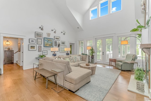 living room with access to exterior, a wealth of natural light, light hardwood / wood-style flooring, and high vaulted ceiling