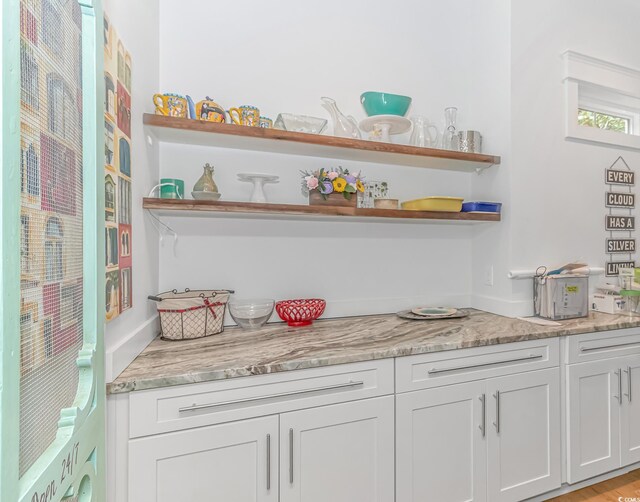 interior space featuring white cabinets, light wood-type flooring, and light stone counters