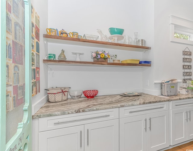 bar with white cabinetry and light stone counters