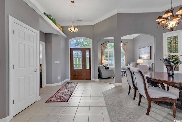 tiled entryway featuring an inviting chandelier and ornamental molding