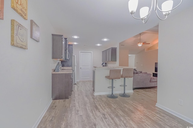 kitchen with lofted ceiling, ceiling fan, light hardwood / wood-style flooring, gray cabinets, and a breakfast bar