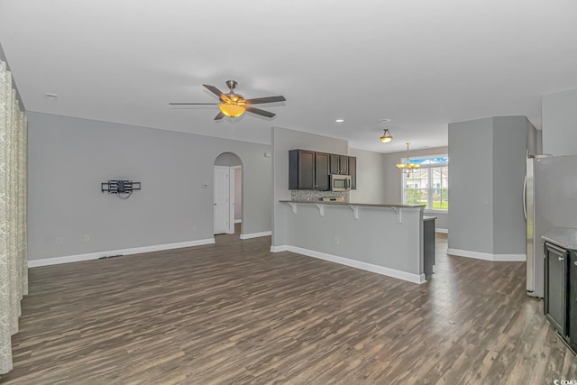 unfurnished living room with dark hardwood / wood-style flooring and ceiling fan with notable chandelier