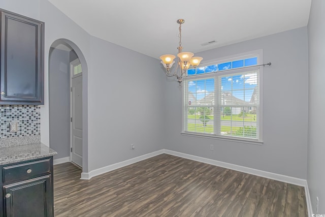 unfurnished dining area featuring a notable chandelier and dark hardwood / wood-style floors