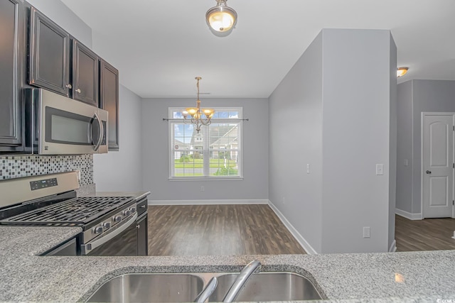 kitchen with dark brown cabinets, stainless steel appliances, light stone counters, decorative backsplash, and decorative light fixtures