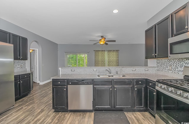 kitchen featuring kitchen peninsula, stainless steel appliances, sink, ceiling fan, and wood-type flooring