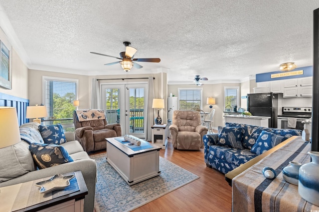 living room with a textured ceiling, wood finished floors, a ceiling fan, french doors, and crown molding