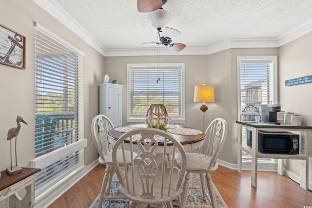 dining area with plenty of natural light, crown molding, and wood finished floors