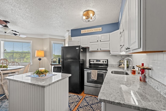 kitchen with a center island, backsplash, freestanding refrigerator, a sink, and stainless steel range with electric stovetop