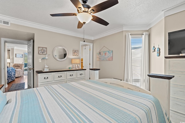 bedroom with crown molding, visible vents, a ceiling fan, a textured ceiling, and wood finished floors