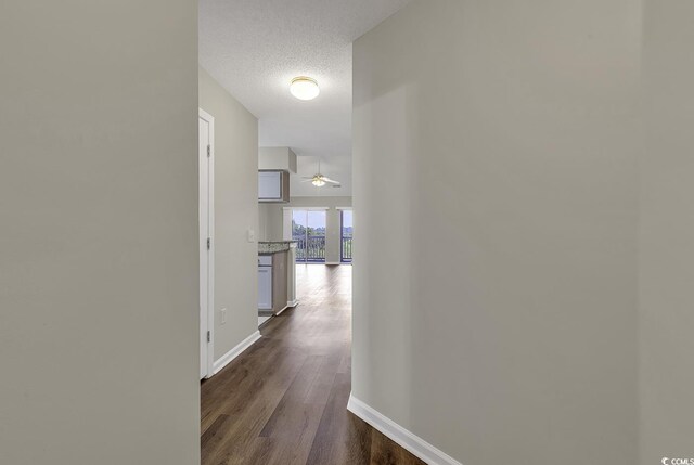 hallway with wood-type flooring and a textured ceiling