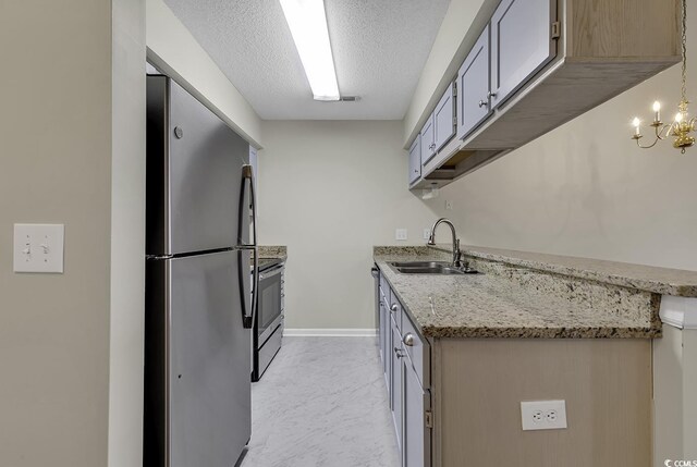 kitchen featuring light tile patterned flooring, a chandelier, sink, appliances with stainless steel finishes, and a textured ceiling