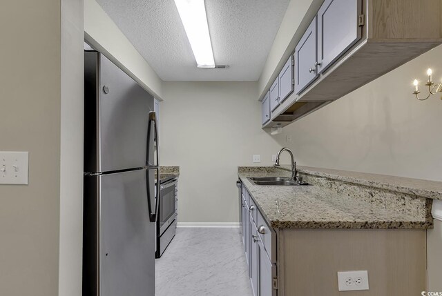 kitchen featuring light tile patterned flooring, a textured ceiling, light stone counters, stainless steel appliances, and sink