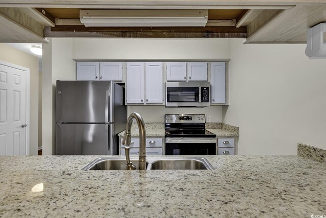 kitchen featuring sink, light stone countertops, stainless steel appliances, and white cabinetry