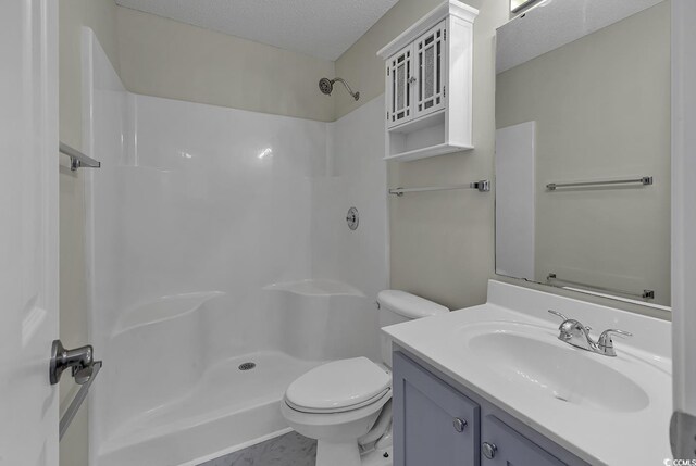 bathroom with tile patterned flooring, a shower, a textured ceiling, toilet, and vanity