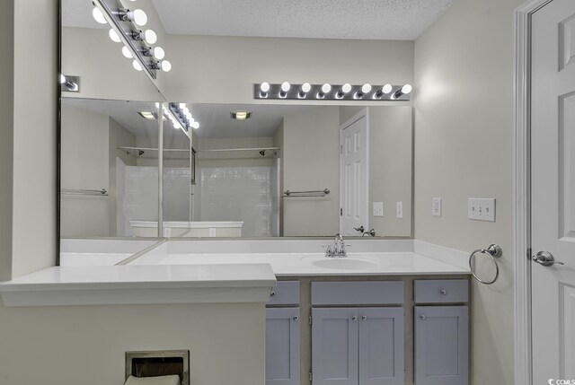 bathroom with walk in shower, vanity, and a textured ceiling