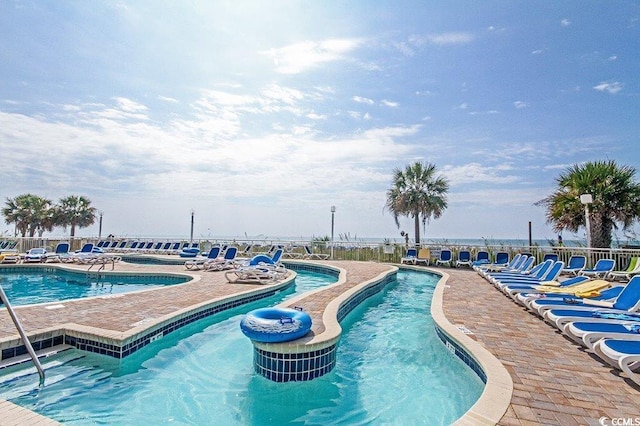 view of pool with a patio and a water view