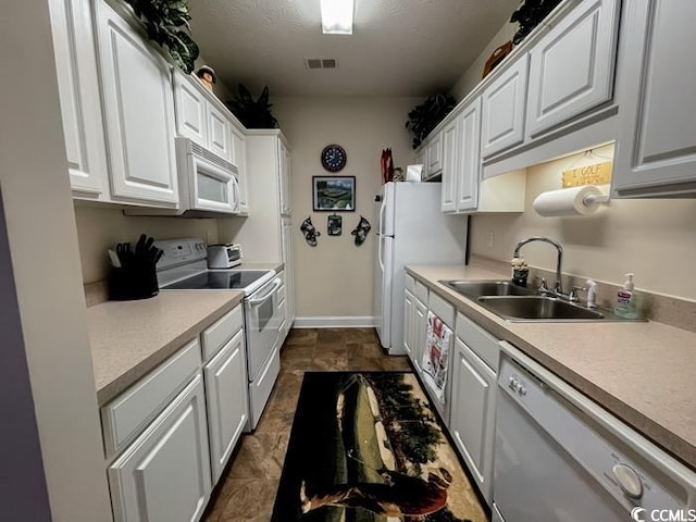 kitchen featuring sink, dark tile patterned flooring, white appliances, and white cabinets