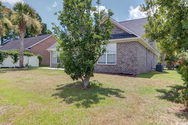 view of side of home featuring a yard and central AC