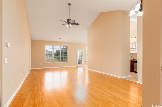 unfurnished living room featuring sink, ceiling fan with notable chandelier, vaulted ceiling, and light wood-type flooring