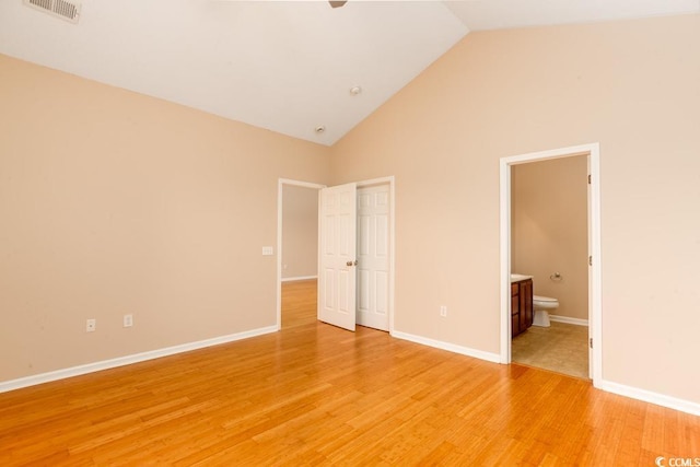 unfurnished bedroom with connected bathroom, high vaulted ceiling, and light hardwood / wood-style floors