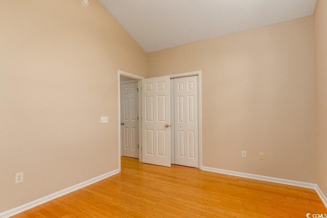 unfurnished bedroom featuring a closet, light hardwood / wood-style flooring, and vaulted ceiling