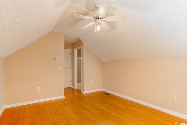 additional living space featuring hardwood / wood-style floors, ceiling fan, lofted ceiling, and a textured ceiling