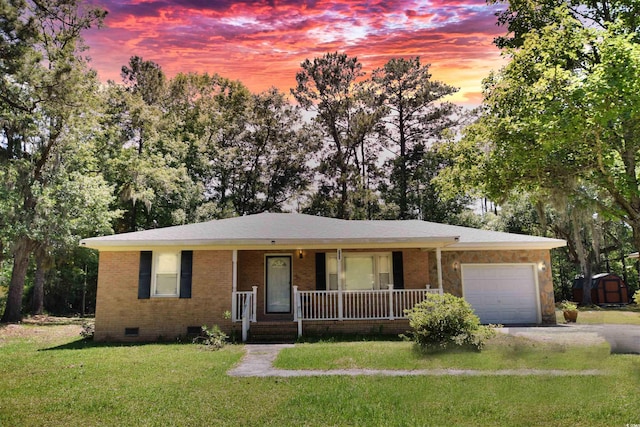 single story home with covered porch, a garage, and a lawn