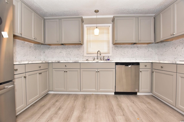 kitchen with sink, a textured ceiling, decorative light fixtures, gray cabinets, and appliances with stainless steel finishes