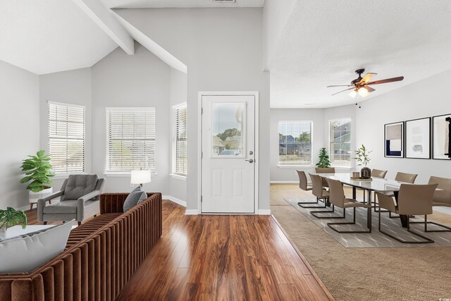 unfurnished living room with high vaulted ceiling, dark carpet, ceiling fan, and beam ceiling