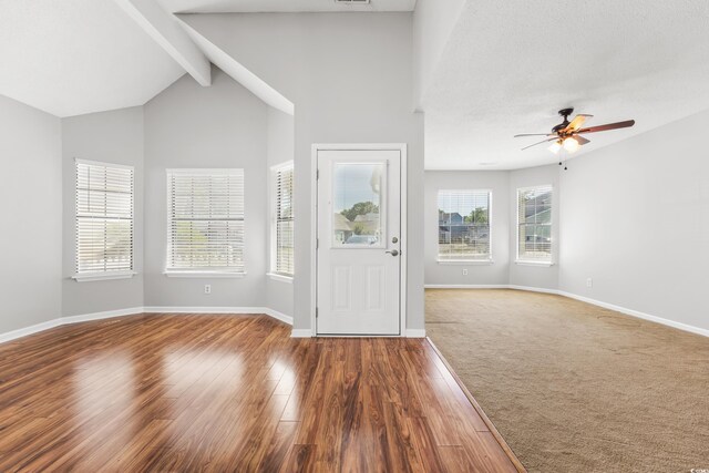 unfurnished living room featuring high vaulted ceiling, beamed ceiling, and wood-type flooring