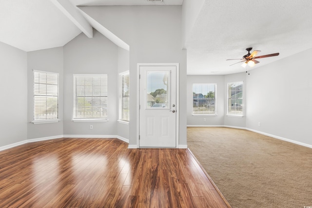 foyer entrance with a textured ceiling, hardwood / wood-style floors, vaulted ceiling with beams, and ceiling fan