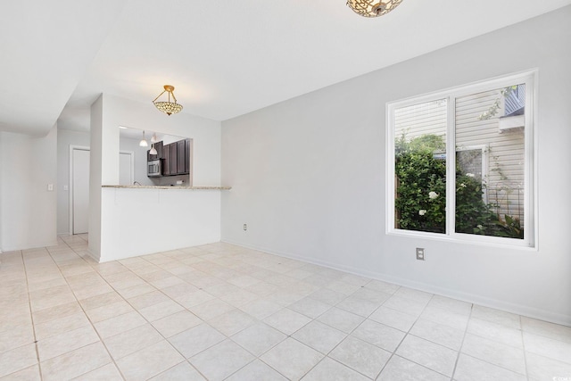 unfurnished living room featuring light tile patterned flooring and baseboards