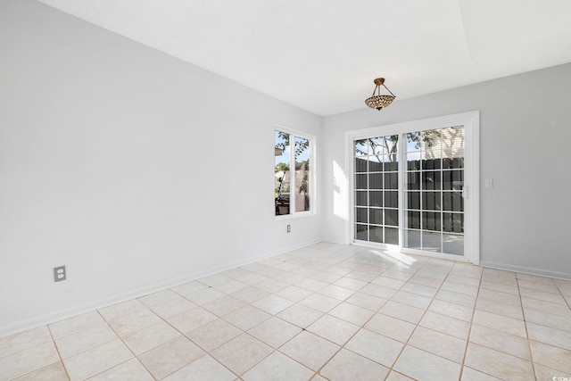 spare room featuring light tile patterned floors and baseboards