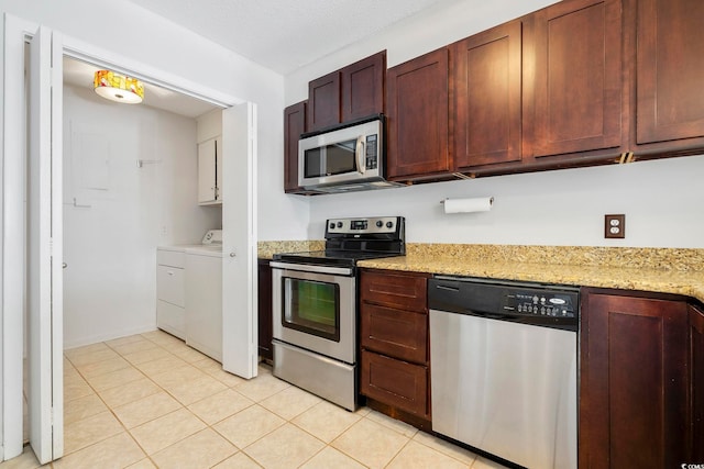 kitchen with light tile patterned floors, light stone counters, stainless steel appliances, and separate washer and dryer