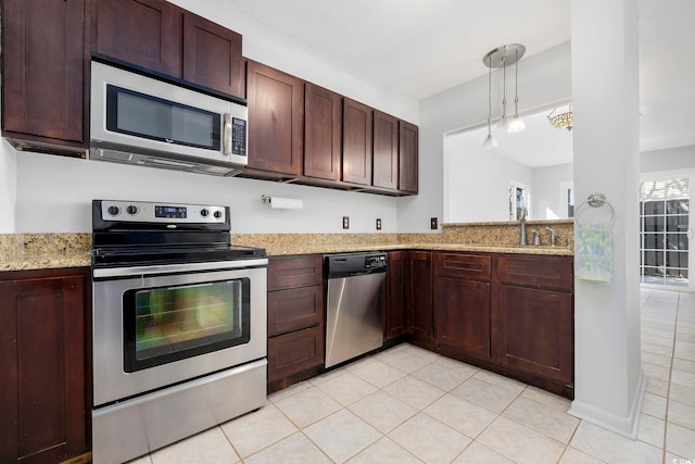 kitchen featuring light stone counters, decorative light fixtures, stainless steel appliances, a sink, and light tile patterned flooring