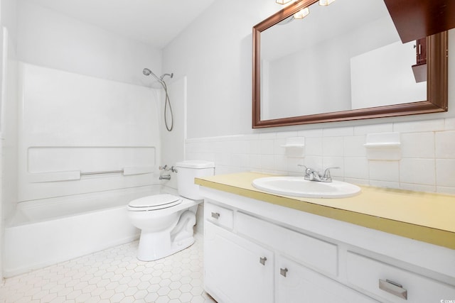 bathroom featuring toilet, a wainscoted wall, vanity, tile walls, and washtub / shower combination